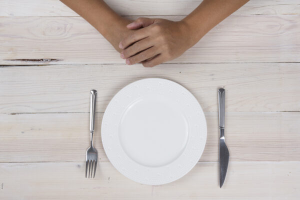 Folded hands and empty plate